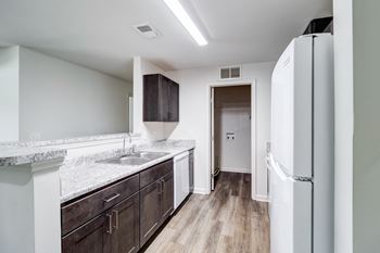 A kitchen with a white fridge and brown cabinets. at Ada Park Apartments, Virginia, 23601